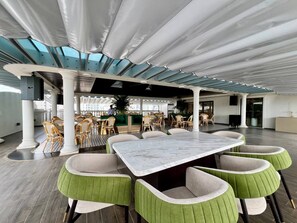A spacious conference room with a large marble table surrounded by green upholstered chairs, white columns, and a high ceiling with skylights. - Lavia Hotel (Phnom Penh)