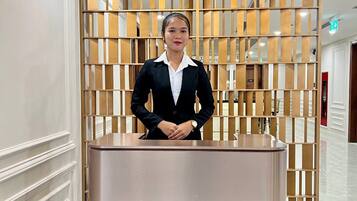 A reception desk with a modern design, a wooden slatted backdrop, and a ceiling light fixture.
