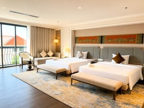 A hotel room with three beds, a sofa, a chair, and a large window. - Lavia Hotel (Phnom Penh)