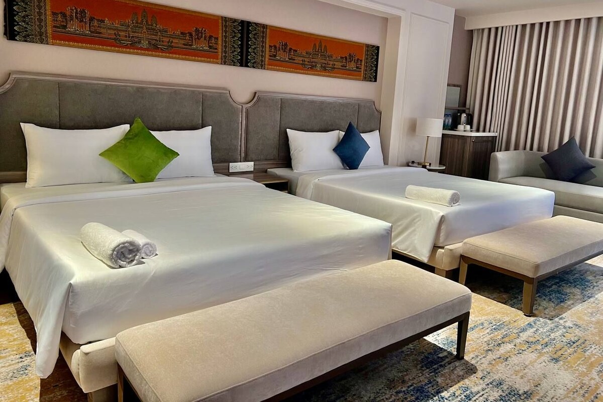 Ett hotellrum med två sängar, en soffa och ett skrivbord.