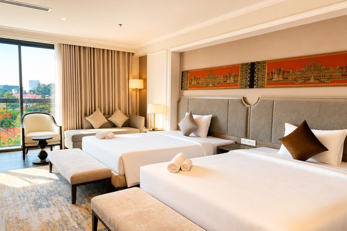 Ett hotellrum med tre sängar, en sittgrupp och ett stort fönster med utsikt över staden.