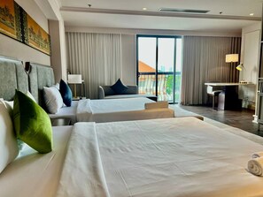 Habitación de hotel con dos camas, un escritorio y vistas al exterior.