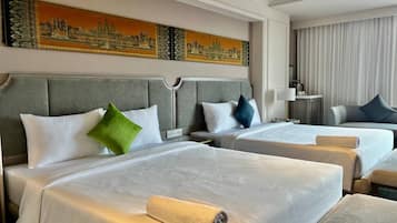 A hotel room with two beds, a headboard, and a large window with curtains.