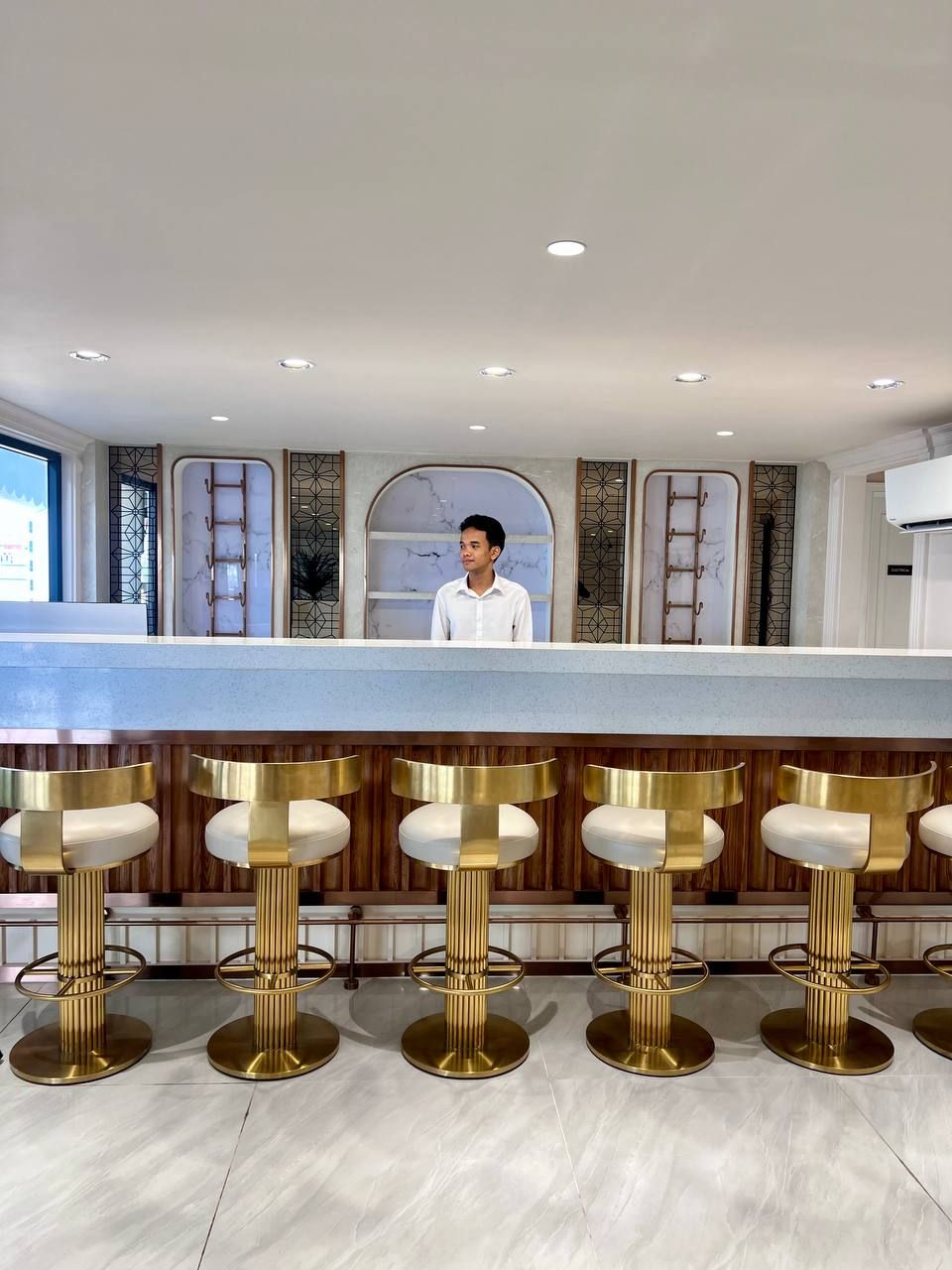 Eine Bar mit einer Theke und fünf Barhocker mit goldenen Füßen.