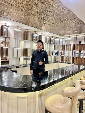 A modern bar area with a marble countertop, bar stools, and a decorative ceiling. - Lavia Hotel (Phnom Penh)