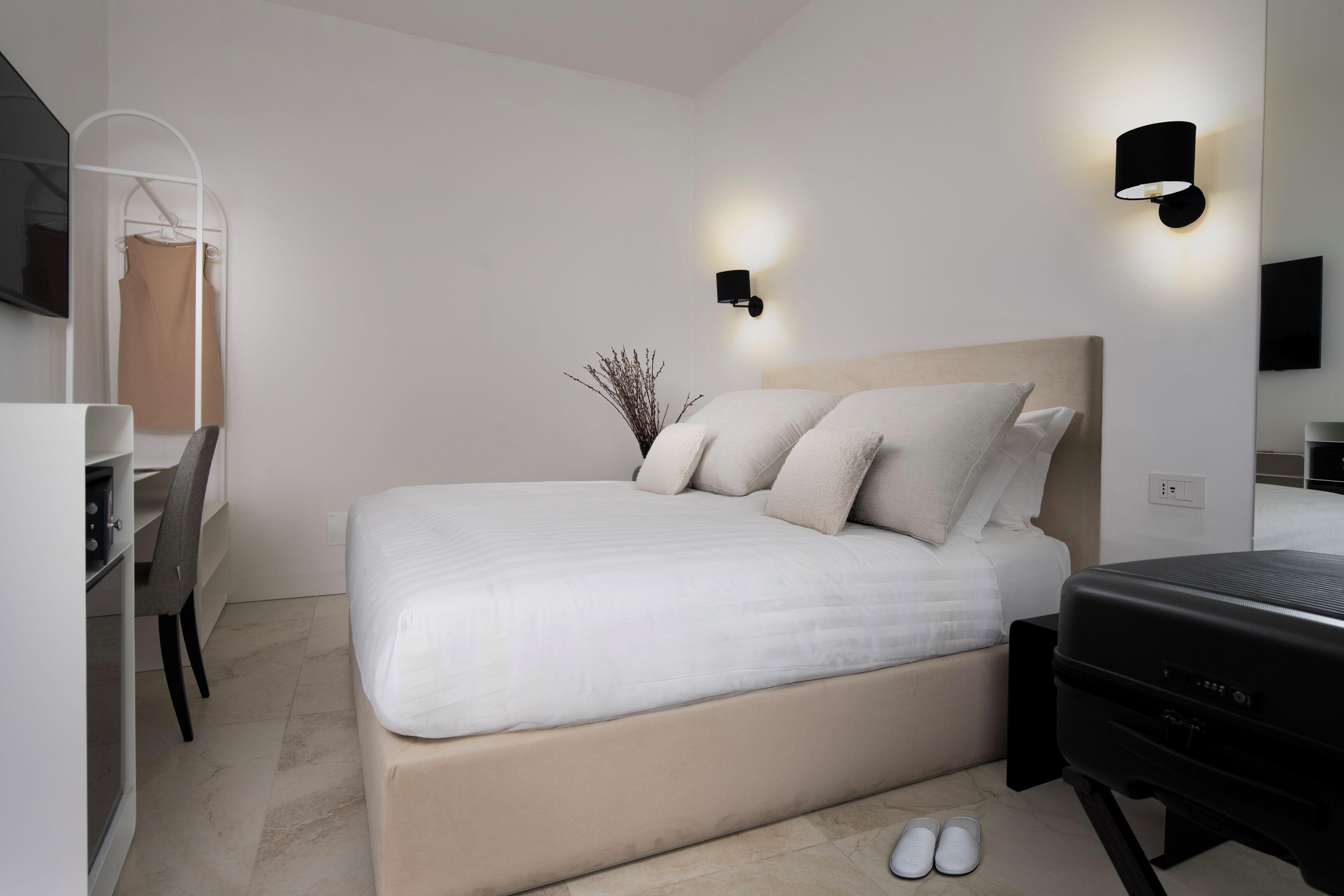 Un dormitorio moderno con cama, mesitas de noche, un escritorio y un televisor.