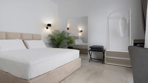 A modern hotel room with a large bed, a small table, a chair, a mirror, and a bathtub.
