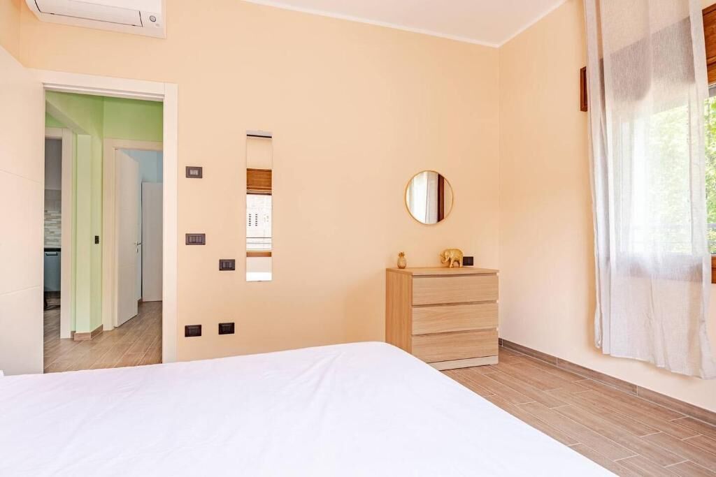 A bedroom with a bed, a dresser, a mirror, and a door leading to another room.