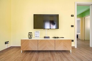 En moderne stue med et fladskærms-TV monteret på et træskab, en lampe og en dekorativ genstand på skabet.
