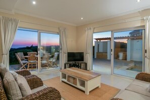 A spacious living room with a television, comfortable seating, and a view of the outdoors. - Pezula Fairlead Luxury 7A  (Knysna)