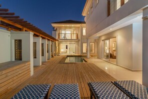 A modern outdoor pool area with wooden decking and lounge chairs. - Pezula Fairlead Luxury 7A  (Knysna)