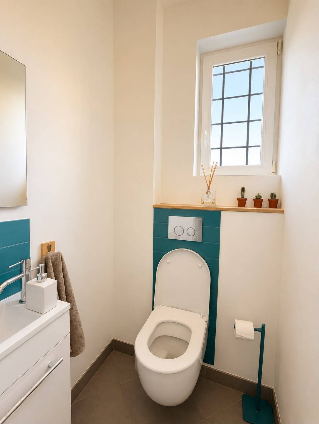 A compact bathroom with a white toilet, a sink with a mirror, and a window above the toilet.
