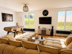 A living room with a foosball table, a sofa set, a television, and a radiator.