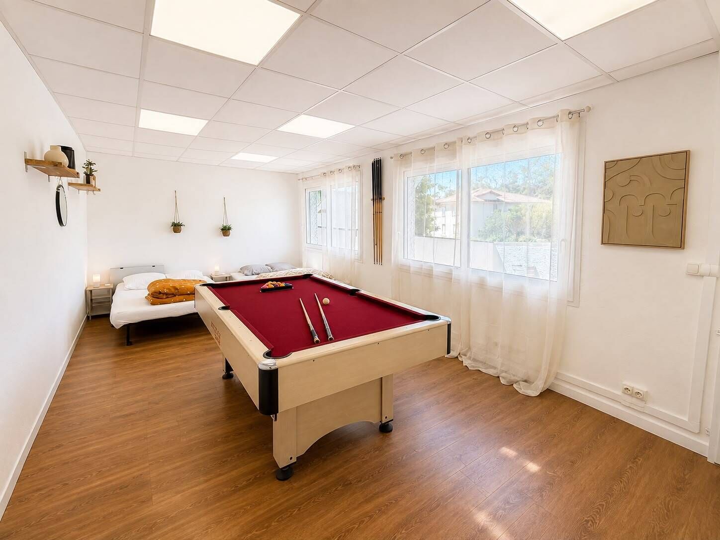 Una habitación con mesa de billar, cama y ventana con cortinas.