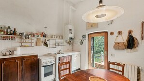 Eine Küche mit weißen Schränken, einem Holzespeisetisch und einer Pendelleuchte.