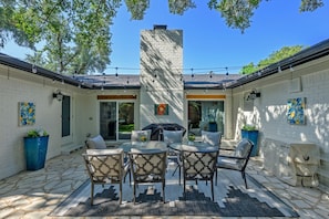 A patio with a brick wall, outdoor furniture, and a chimney.