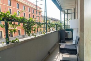 A balcony with a view of buildings, a chair, and a potted plant. - VivimiHome-Suite Casa Degli Specchi (Milan)