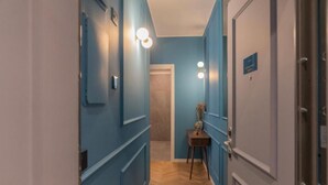 A hallway with blue walls, a wooden floor, and a door with a sign. - VivimiHome-Suite Casa Degli Specchi (Milan)