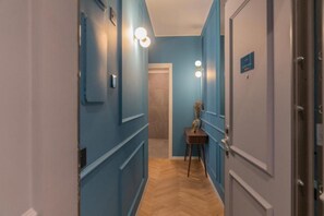 A hallway with blue walls, a wooden floor, and a door with a sign. - VivimiHome-Suite Casa Degli Specchi (Milan)