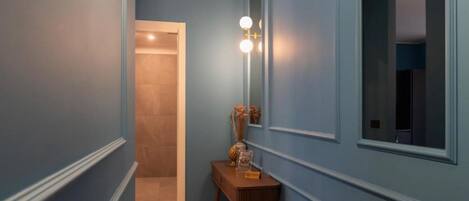 Un pasillo con paredes azules, una consola de madera con adornos y un espejo.