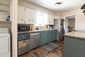 A modern kitchen with white cabinets, stainless steel appliances, and a granite countertop. - The Getaway - Sleeps 12 (Belton)