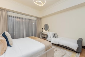 A hotel room with two beds, a desk, a chair, a mirror, and a large window with curtains. - bnbme - Golden Mile 4 - 1BR (Dubai)