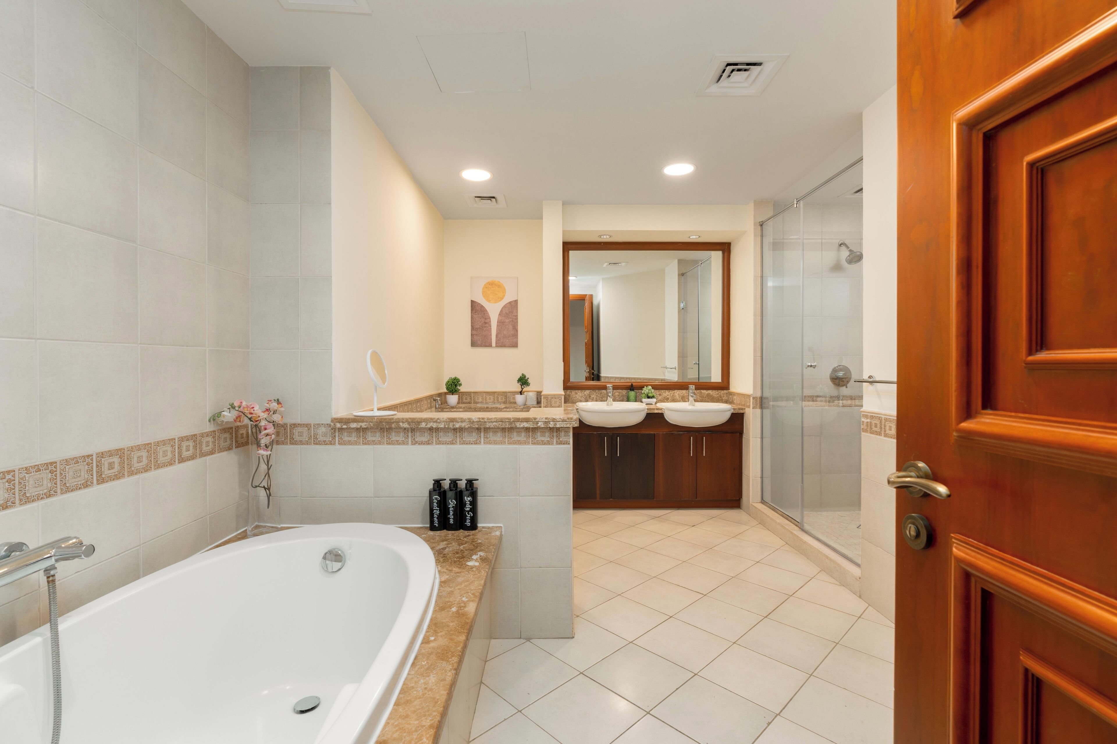 A modern bathroom with a bathtub, two sinks, and a glass-enclosed shower.
