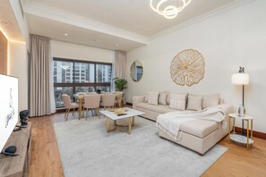 A modern living room with a sofa, coffee table, and dining area. - bnbme - Golden Mile 4 - 1BR (Dubai)