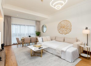 A modern living room with a sofa, coffee table, and dining area. - bnbme - Golden Mile 4 - 1BR (Dubai)