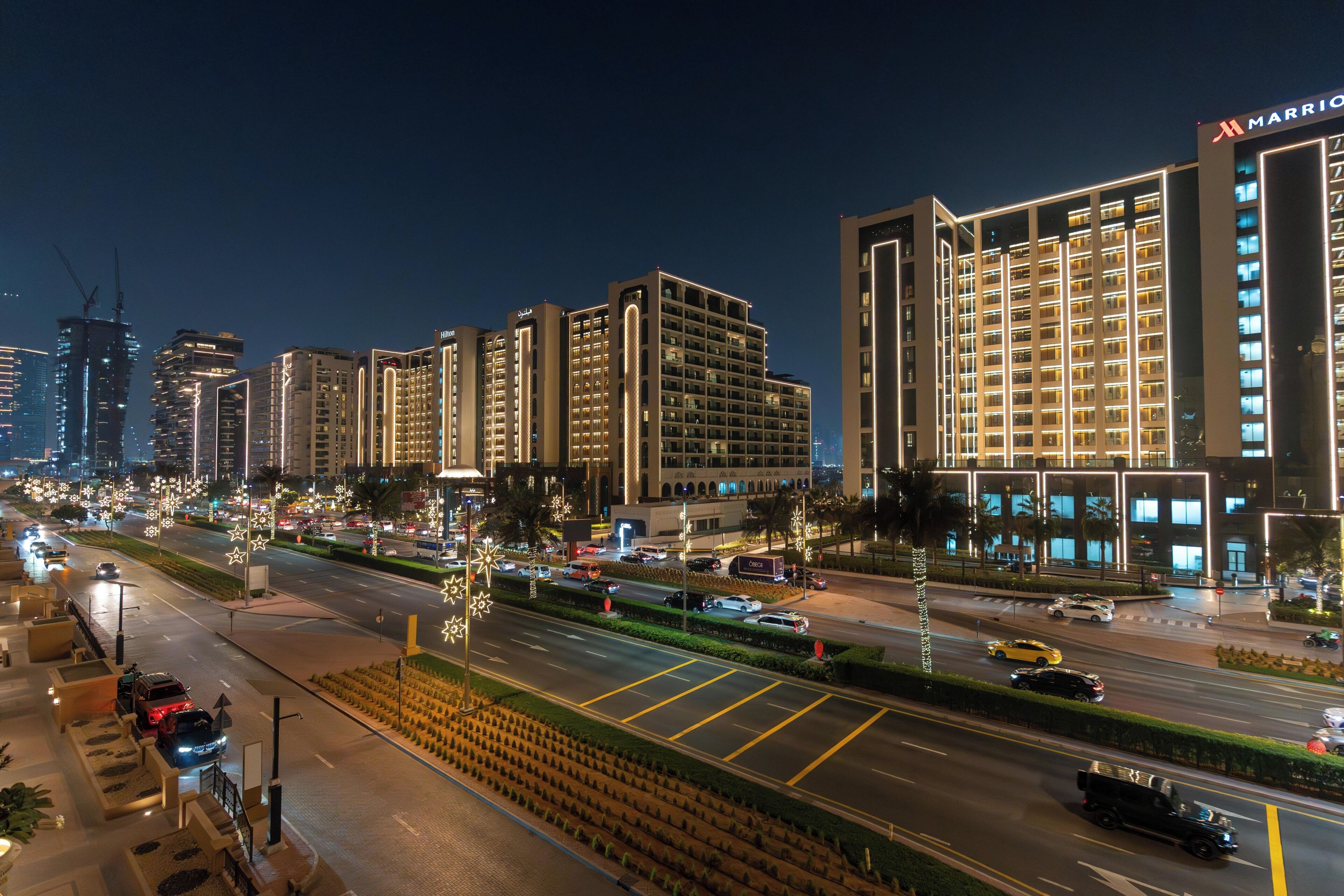 A multi-story hotel with a modern design, featuring illuminated signage and a well-lit facade.