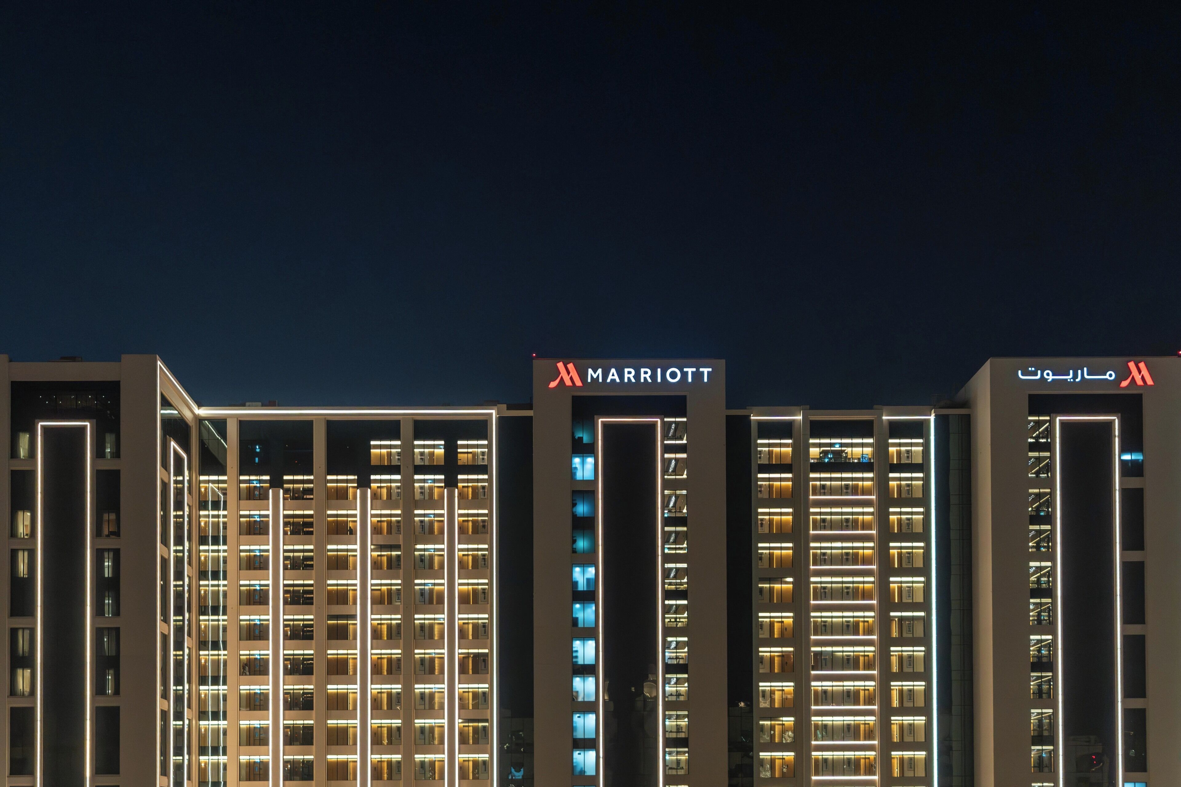 A multi-story hotel building with illuminated signage indicating it is a Marriott property.