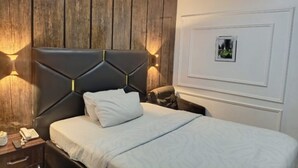 Una habitación de hotel con una cama, una mesita de noche, un teléfono y un cuadro colgado en la pared.