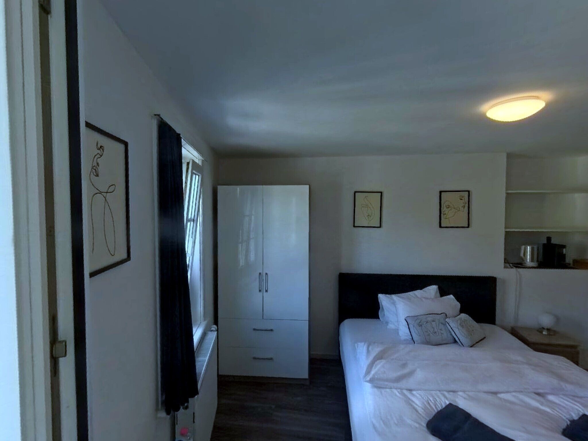 Une chambre d’hôtel comprenant un lit, une armoire, un bureau et une table de chevet.
