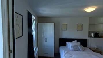A hotel room with a bed, a wardrobe, a desk, and a nightstand.