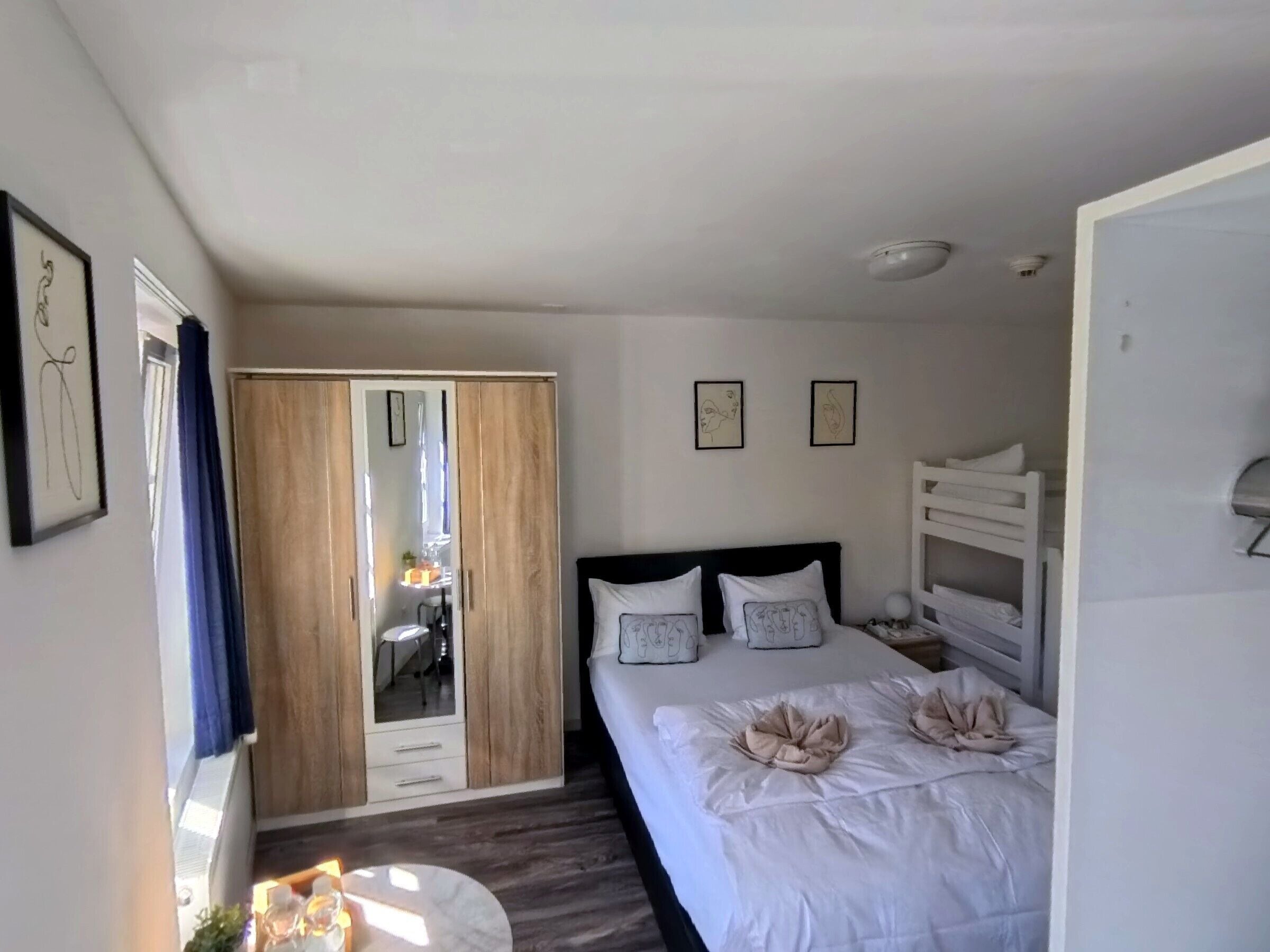 Un dormitorio con cama, armario, espejo y mesita de noche.