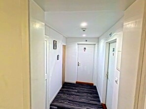Un pasillo estrecho con piso de madera oscura, paredes blancas y puertas con los números 34 y 35.