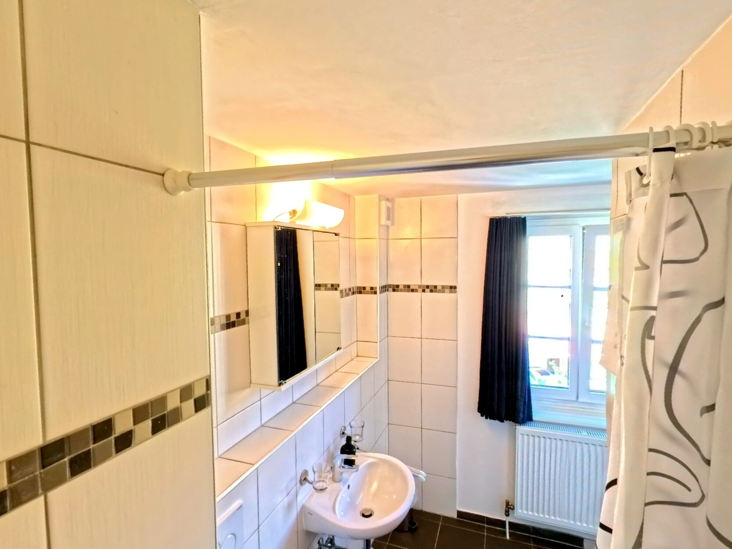A bathroom with a white sink, mirror, and tiled walls.