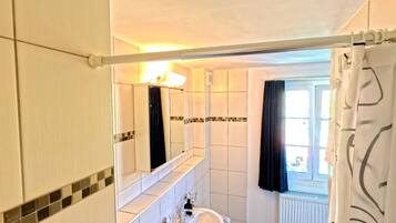 A bathroom with a white sink, mirror, and tiled walls.