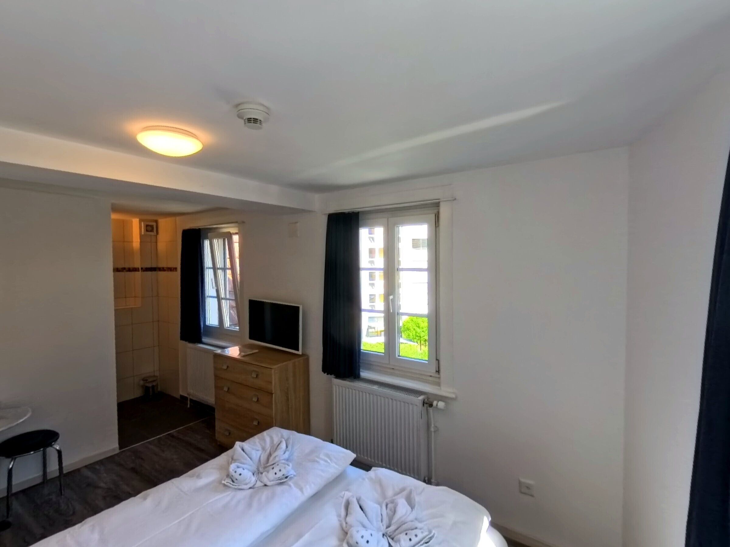 Ein Hotelzimmer mit einem Bett, einem Schrank, einem Fernseher, einem Fenster und einem Badezimmer.