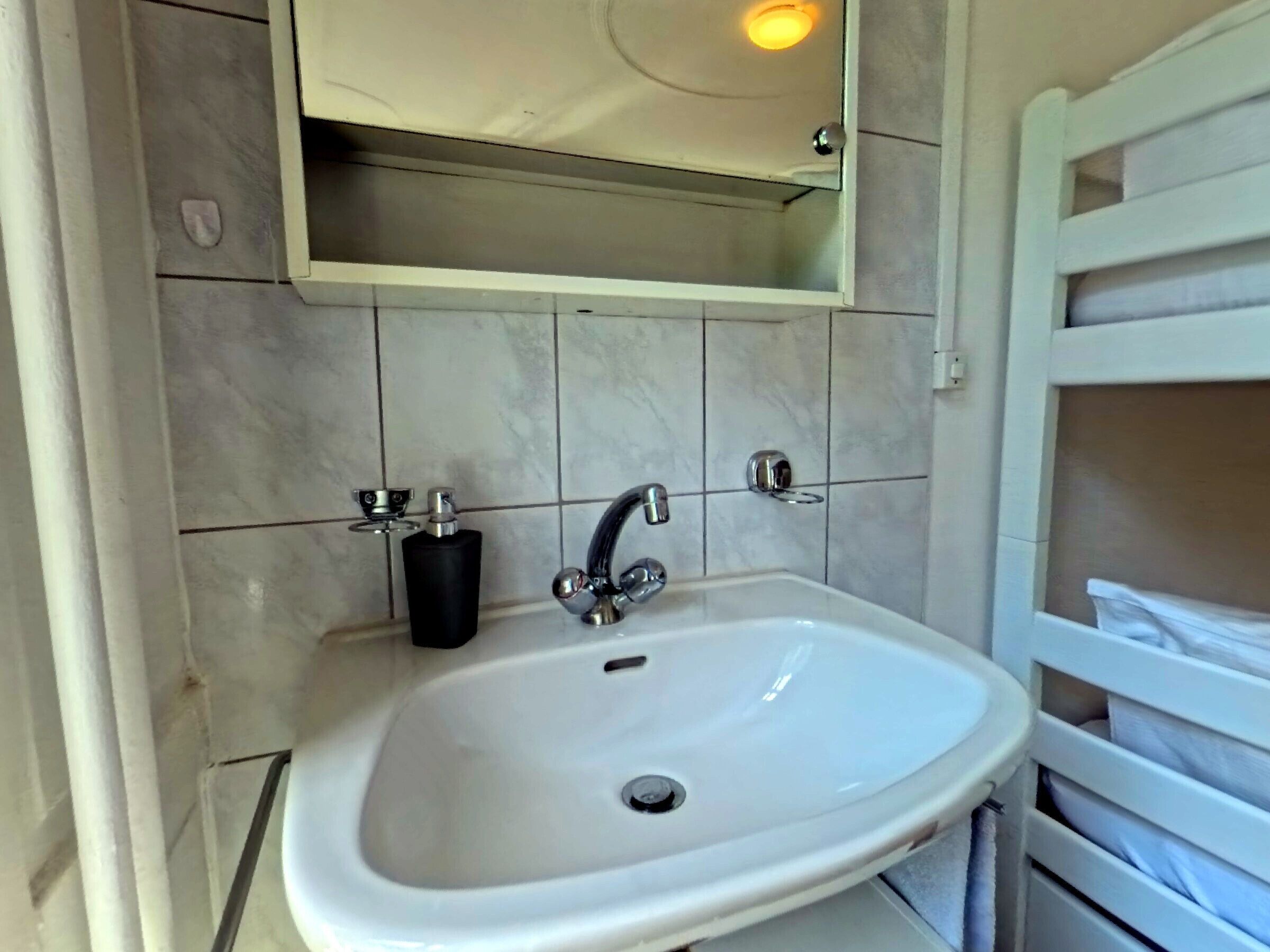A bathroom with a white sink, a mirror above it, and a towel rack to the right.