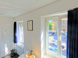 A room with a window, a radiator, a trash bin, and a framed picture on the wall.