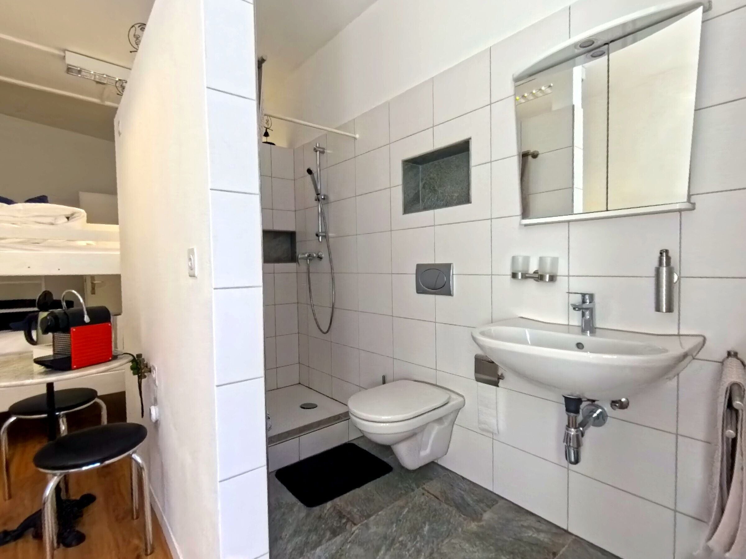 Un baño moderno con ducha, inodoro, lavabo y un espejo pequeño.