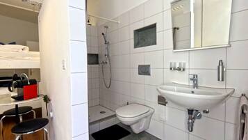 Un baño moderno con ducha, inodoro, lavabo y un espejo pequeño.