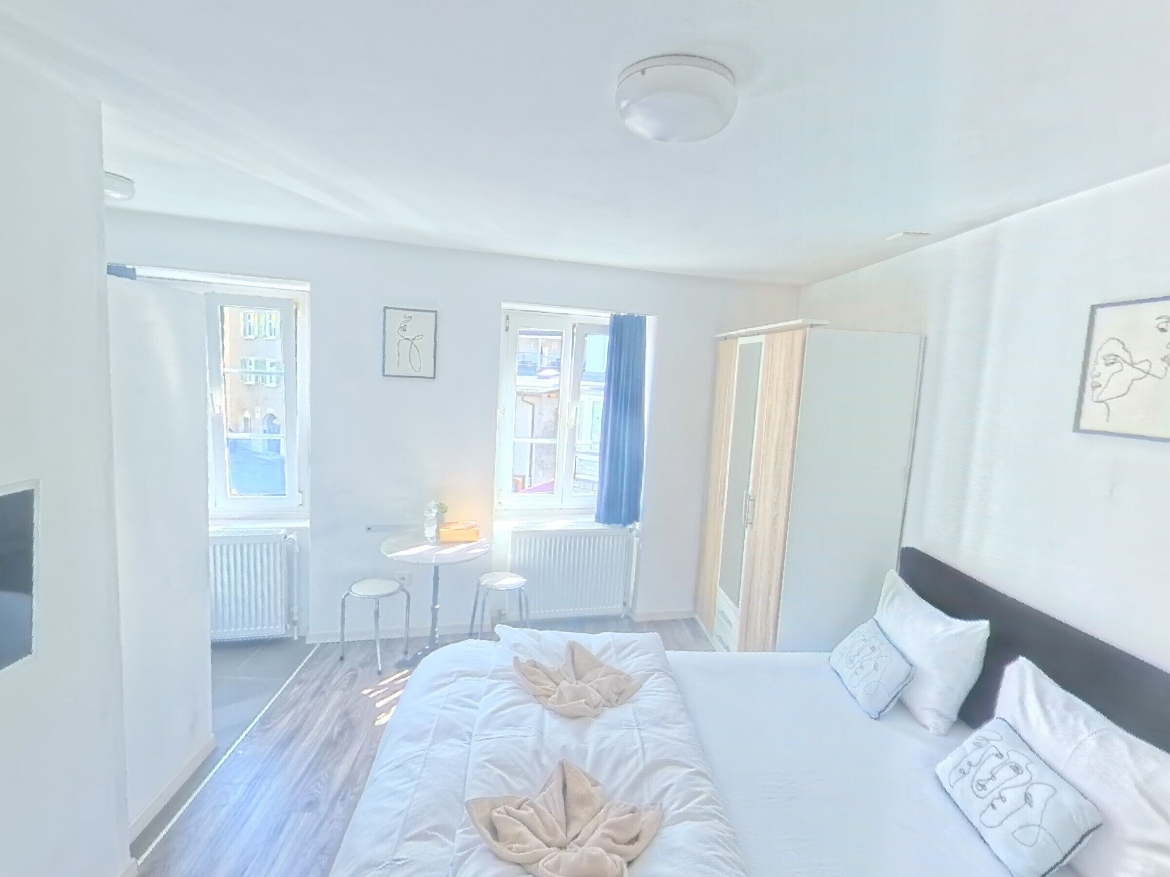 A hotel room with a large bed, a bedside table, a chair, and a window with curtains.