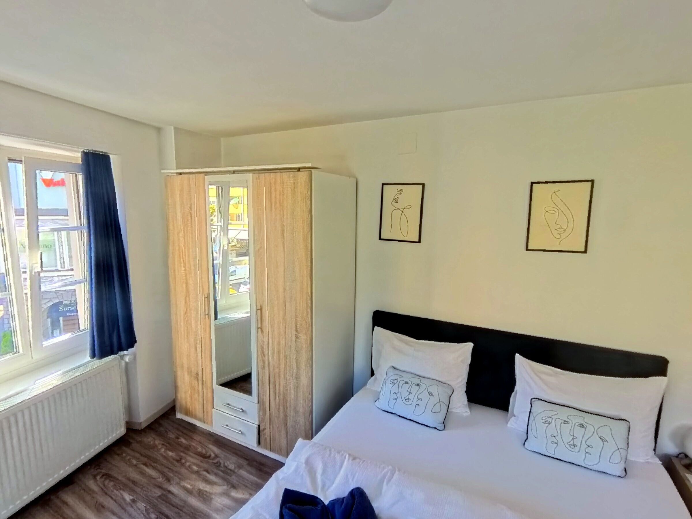 Un dormitorio con una cama, un armario y dos cuadros en la pared.