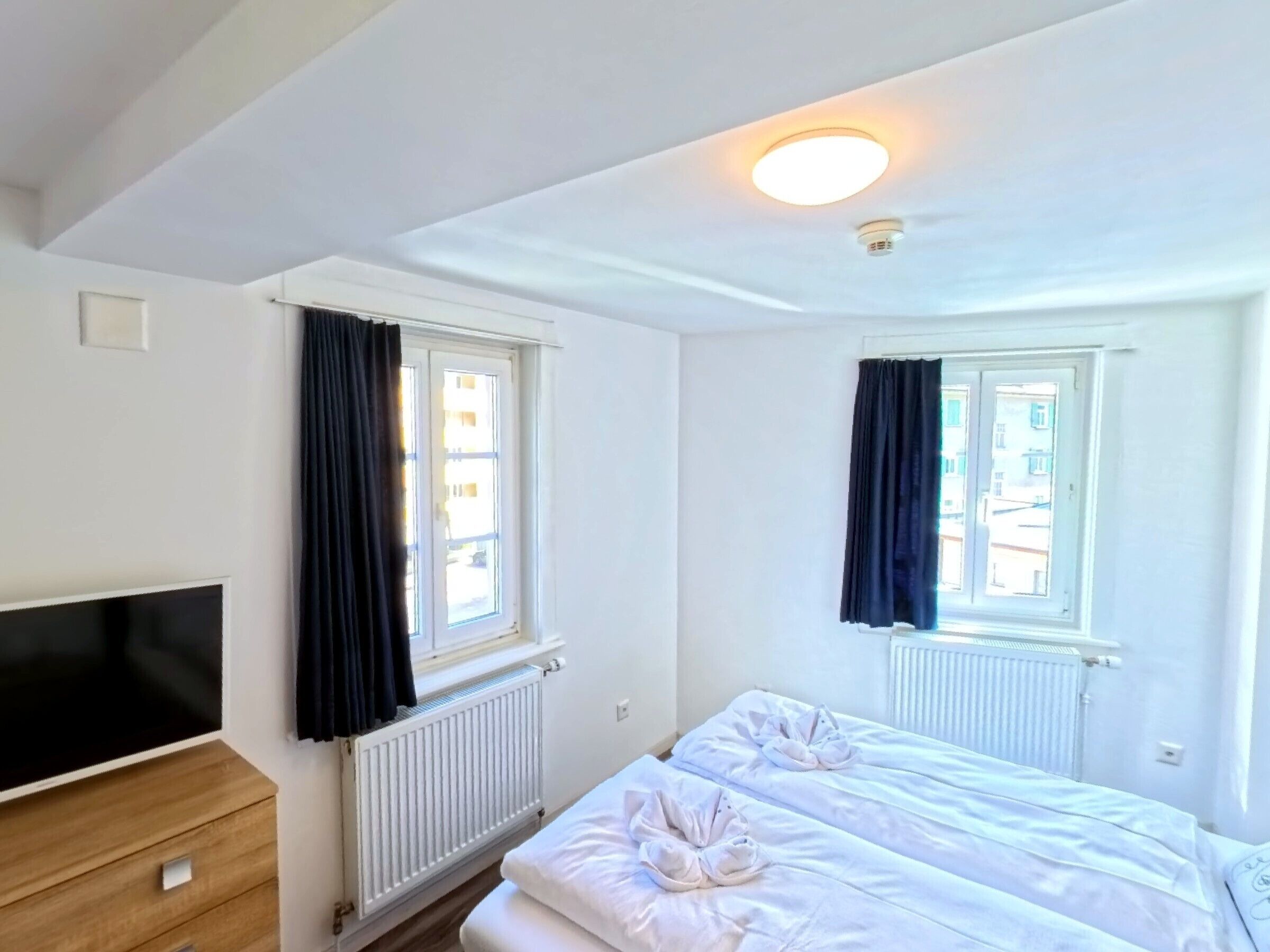 Een hotelkamer met twee bedden, een flatscreen televisie en een radiator.
