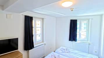 Een hotelkamer met twee bedden, een flatscreen televisie en een radiator.