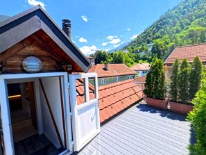 Una terraza de madera con vista a una montaña y casas vecinas.
