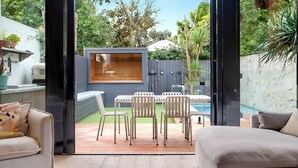 Een open terras met een zwembad, tuinmeubilair en uitzicht op de achtertuin.