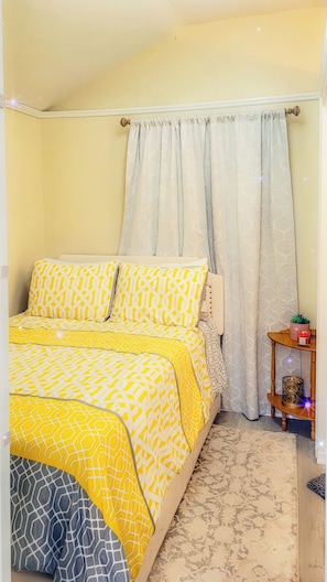 A bedroom with a bed, curtains, a bedside table with a lamp, and a rug. - The Blue Sunshine Retreat (Citra)